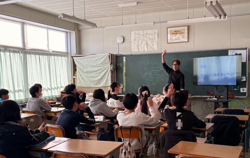 教室で手を挙げる生徒たちと授業を進めるスタッフ