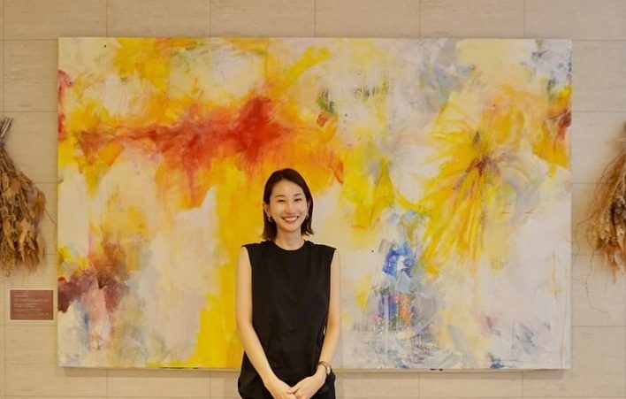 地域のみなさんと描き上げた大きな絵の前に立つ林満里奈さん