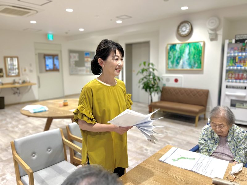 朗読クラブの台本を手に利用者へ話しかける亀井和美さん