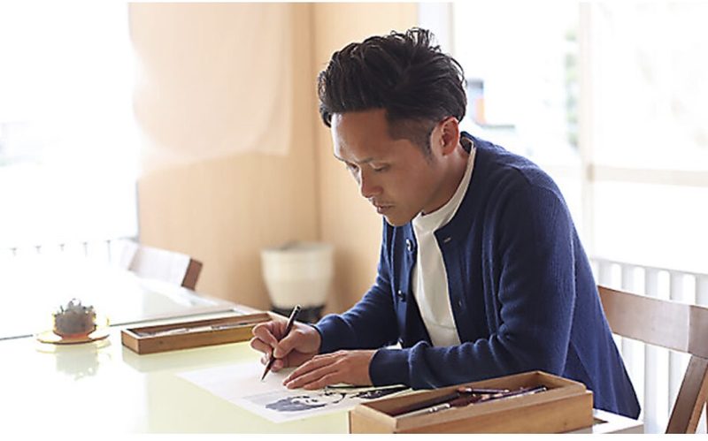 机に向かって資料を書き込むつながるプロジェクトの代表